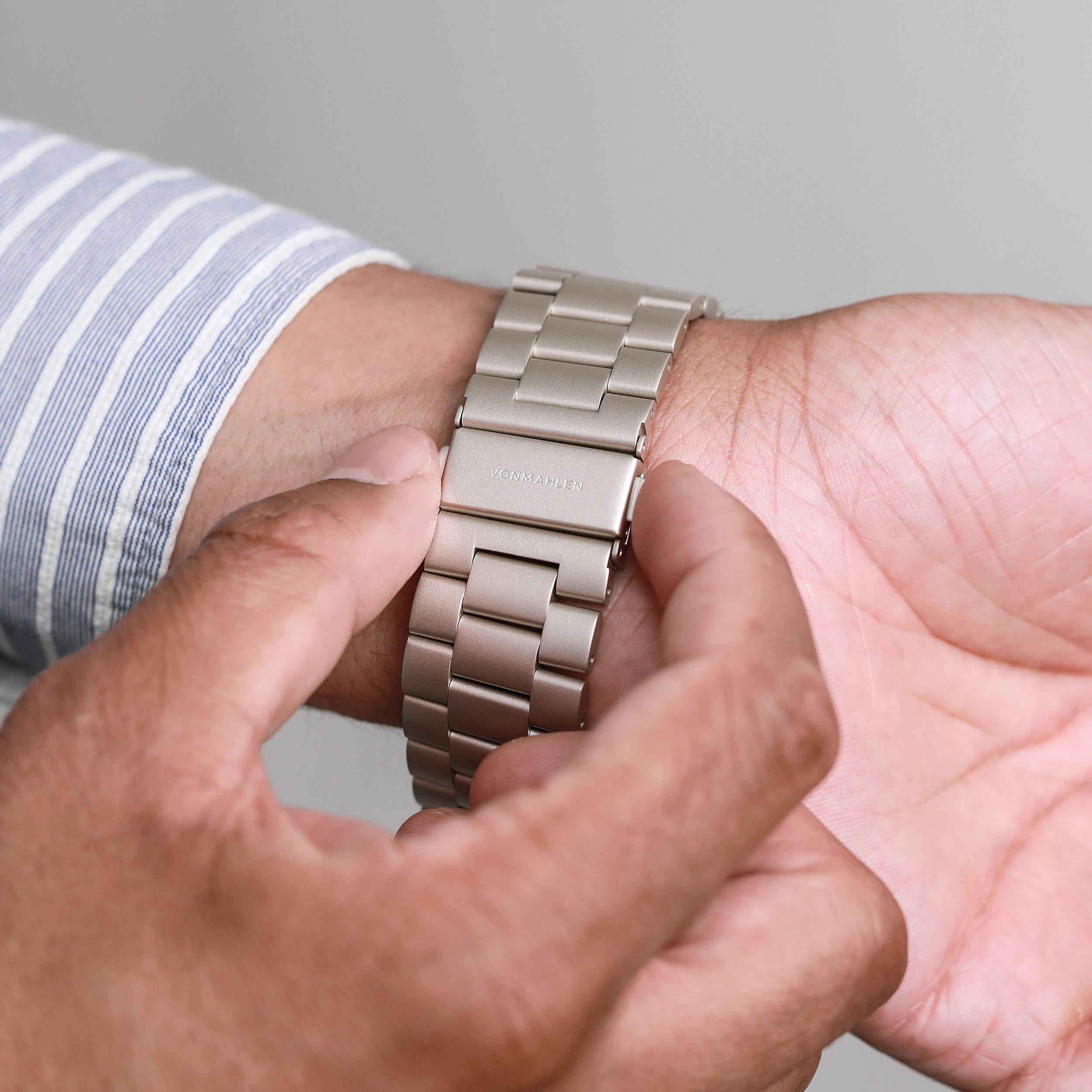 Eine Person passt eine silberne Armbanduhr mit dem Namen VONMAHLEN an.