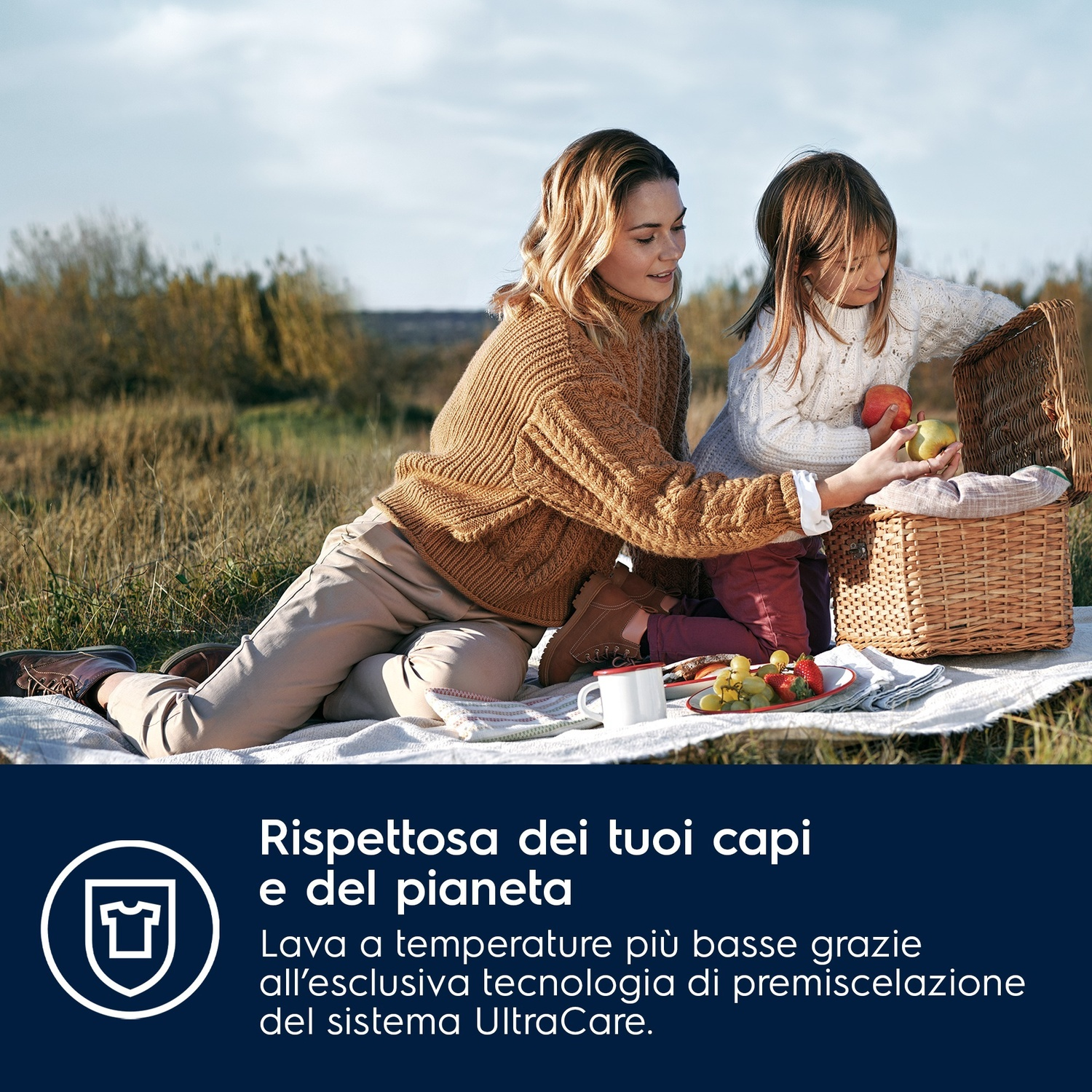 Donna e bambina fanno un picnic all'aperto, prendono frutta da un cesto.