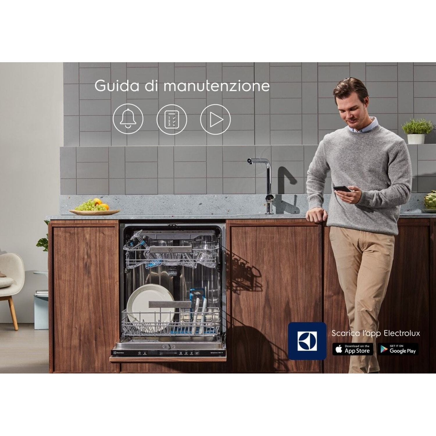 Uomo con smartphone davanti a lavastoviglie aperta e mobili da cucina.
