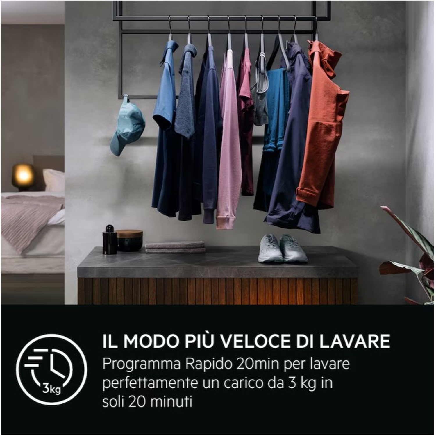 Vestiti appesi a un'asta; letto a sinistra. Scarpe e mobile sotto.