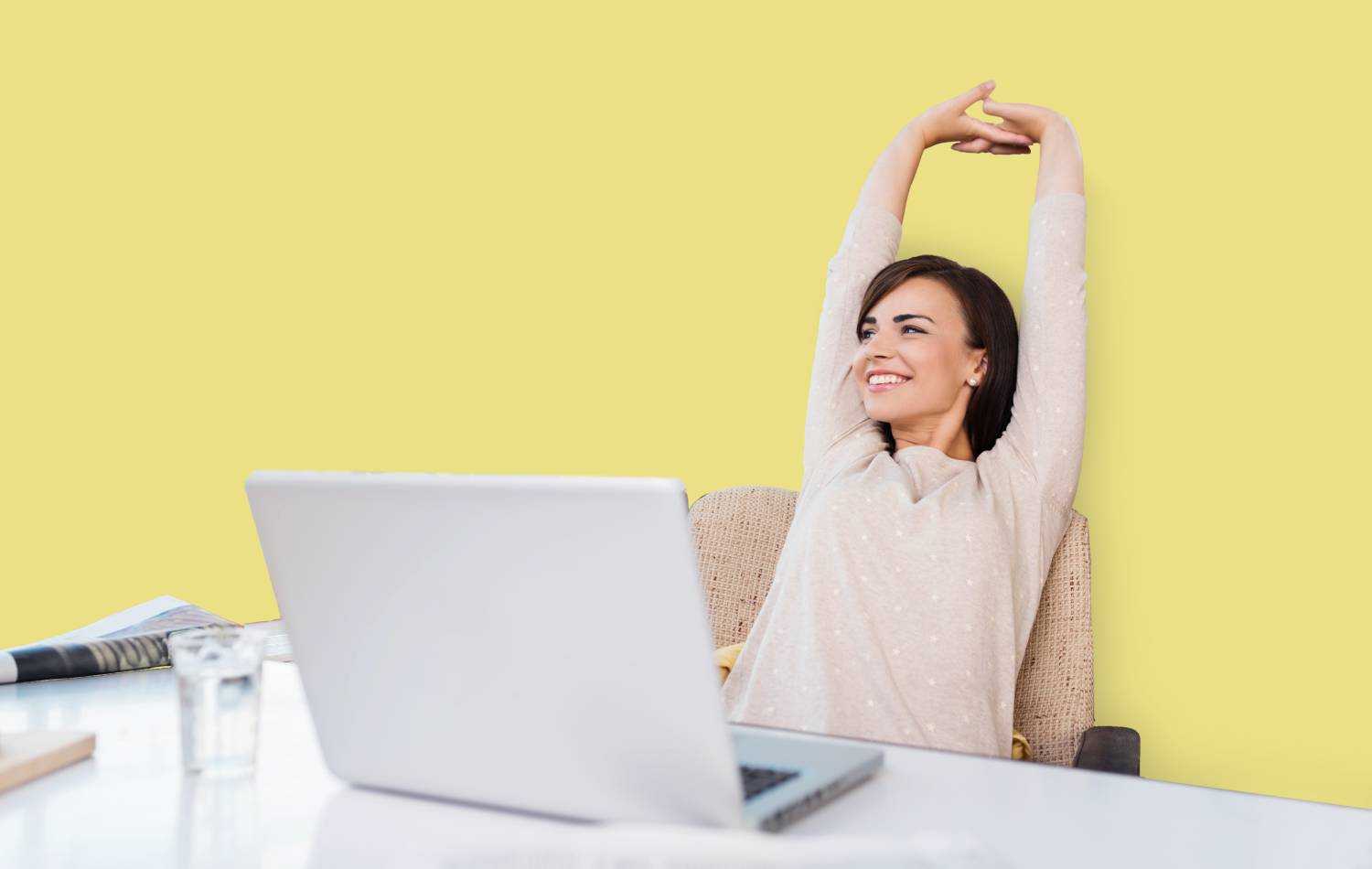 Mujer estirándose frente a una laptop sobre fondo amarillo.