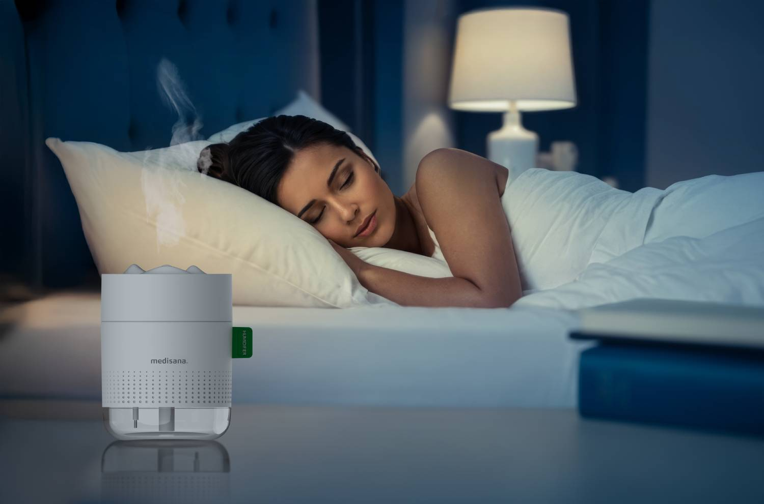 Una mujer duerme en la oscuridad mientras un humidificador emite vapor.