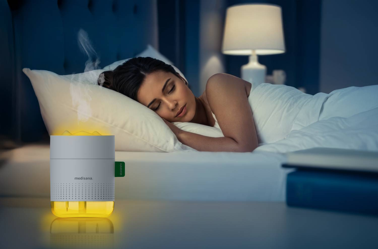 Una mujer duerme en la oscuridad junto a un humidificador brillante.