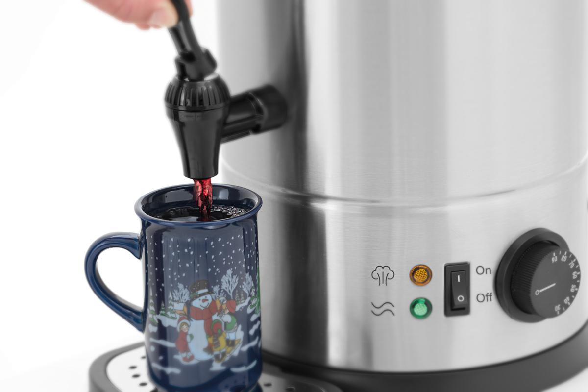 Flüssigkeit fließt aus Zapfhahn in eine Tasse mit Schneemannmotiv.