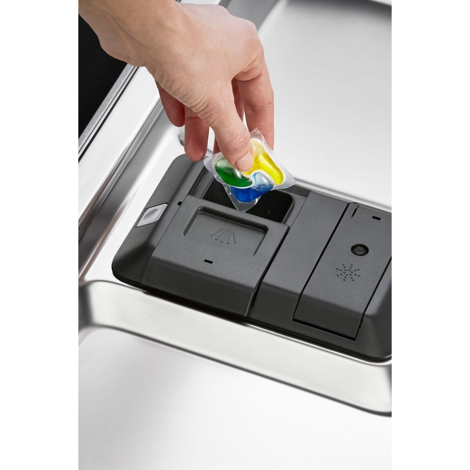 Mano inserisce una capsula detersivo nel dispenser.