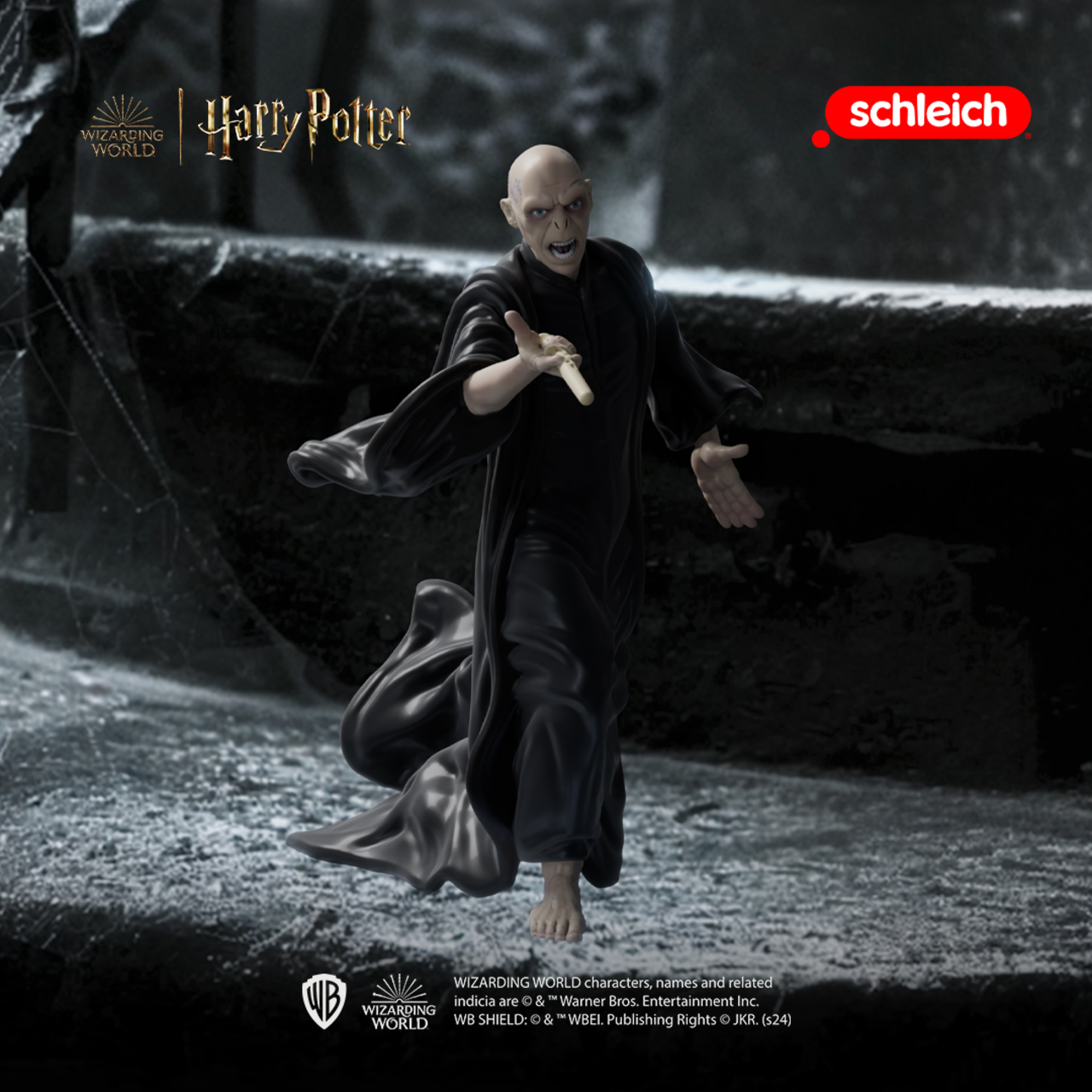 Eine Figur von Voldemort in schwarzem Gewand, die einen Stab hält, auf steinigem Untergrund.