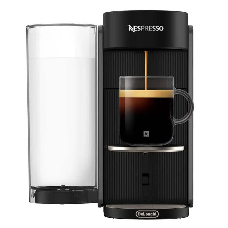Una cafetera Nespresso negra prepara café en una taza de cristal. Un depósito de agua a la izquierda.