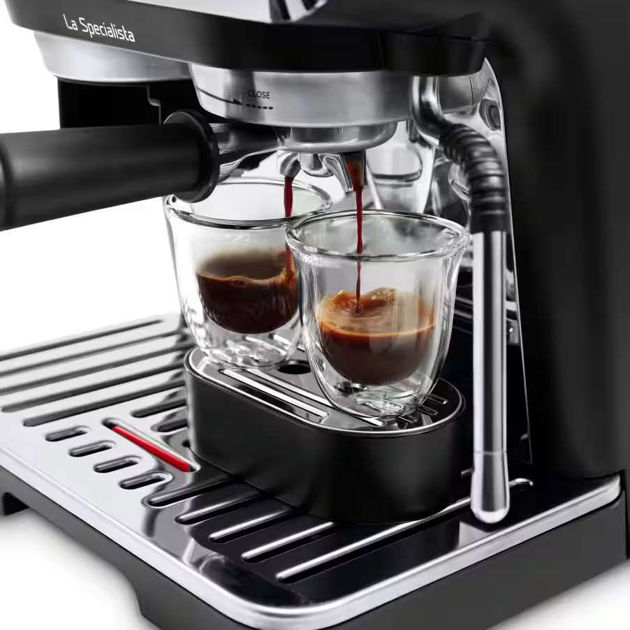 El espresso se vierte en dos vasos transparentes desde una cafetera negra La Specialista.