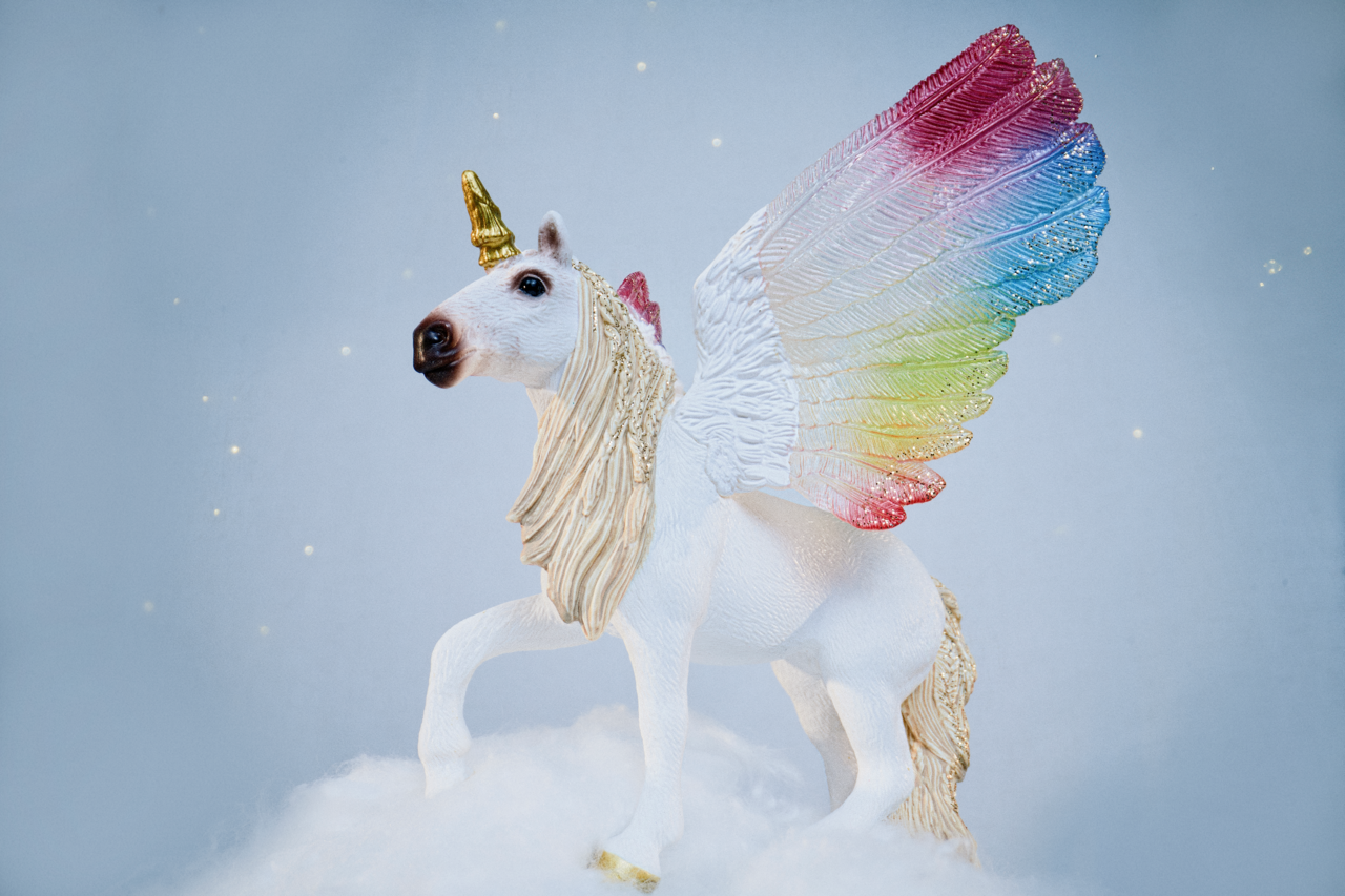 Ein weißes geflügeltes Einhorn mit goldenem Horn steht auf Wolken.