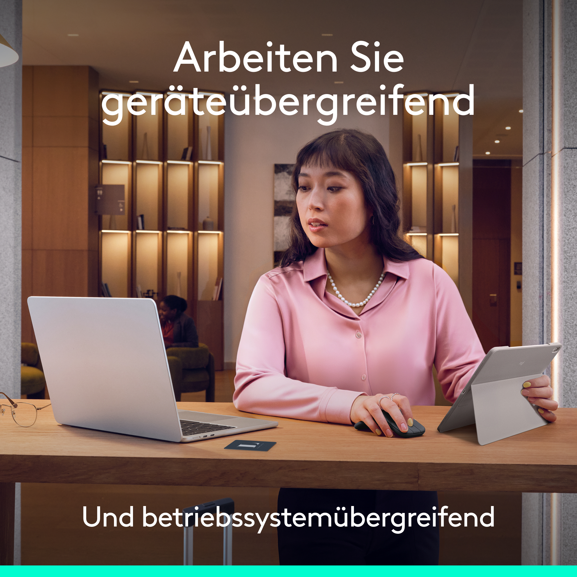 Frau arbeitet am Laptop und Tablet. Grauer Schreibtisch, modern.