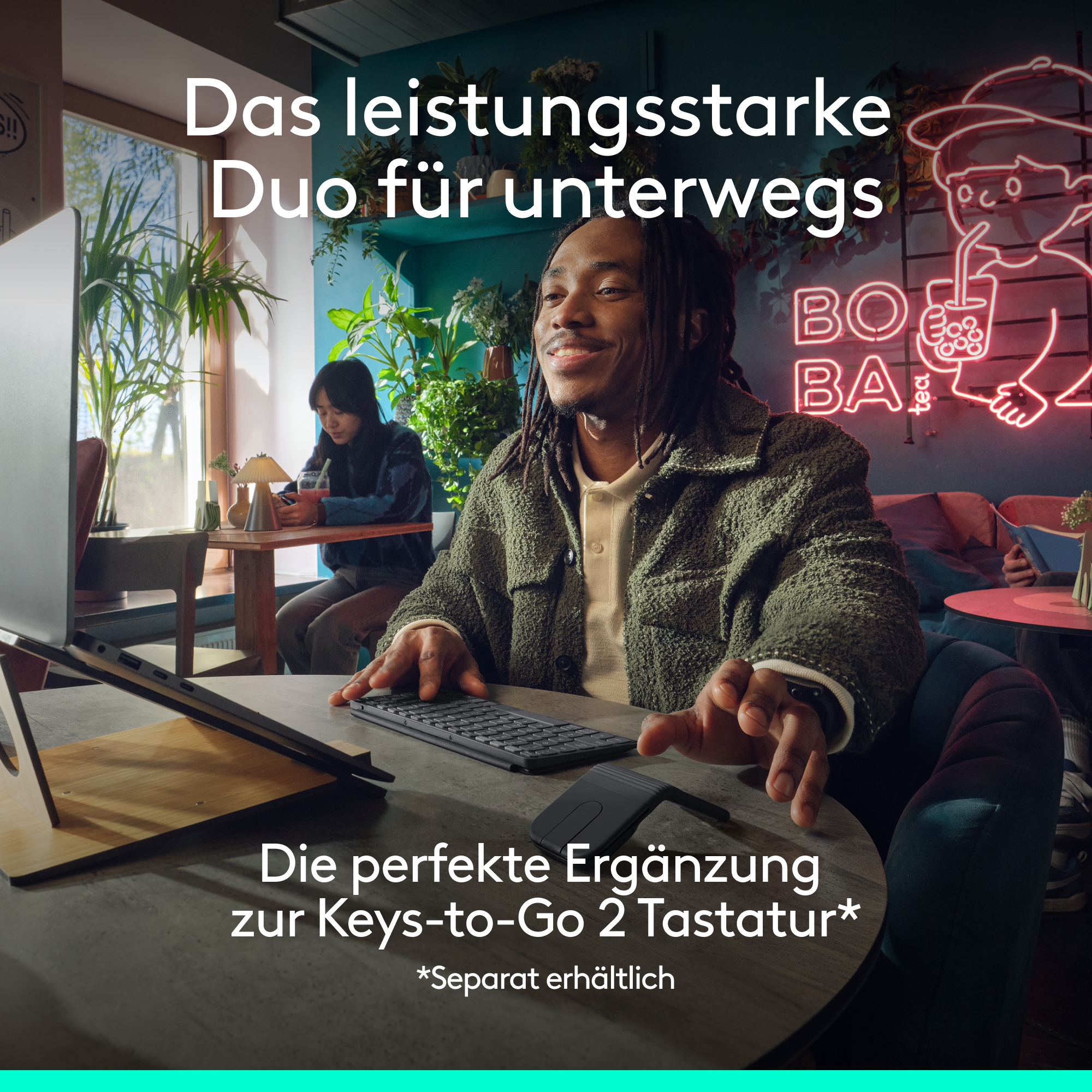 Mann tippt auf Tastatur, Frau trinkt Getränk. Neonlicht im Hintergrund.