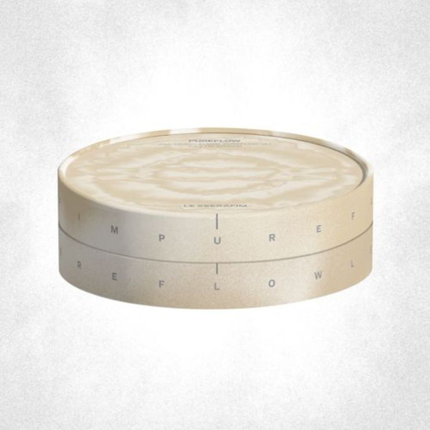 Un récipient rond, de couleur crème, avec un motif ondulé sur le dessus et des lettres sur le côté.