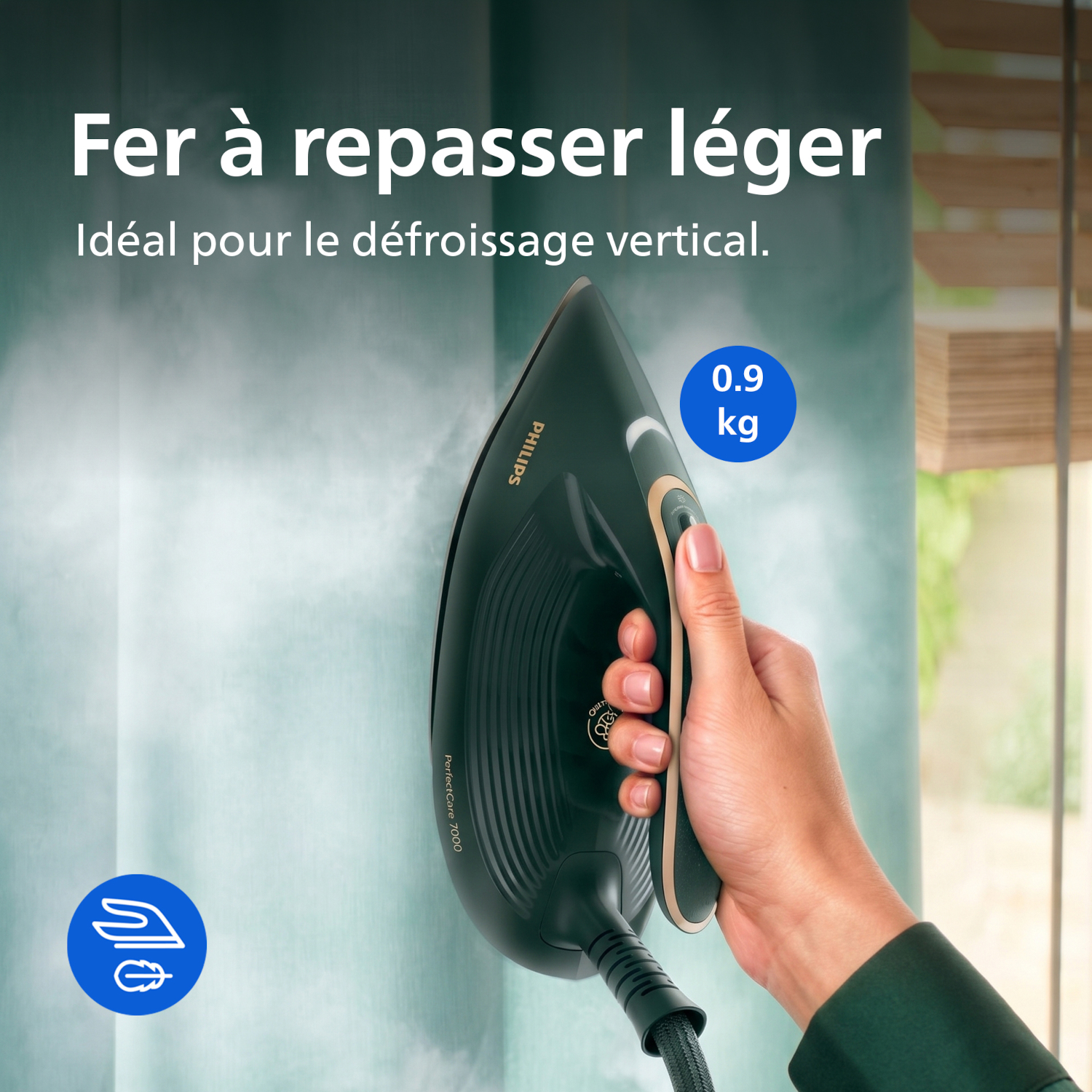 Une main tient un fer Philips vert foncé, qui défroisse un rideau. Il pèse 0,9 kg.
