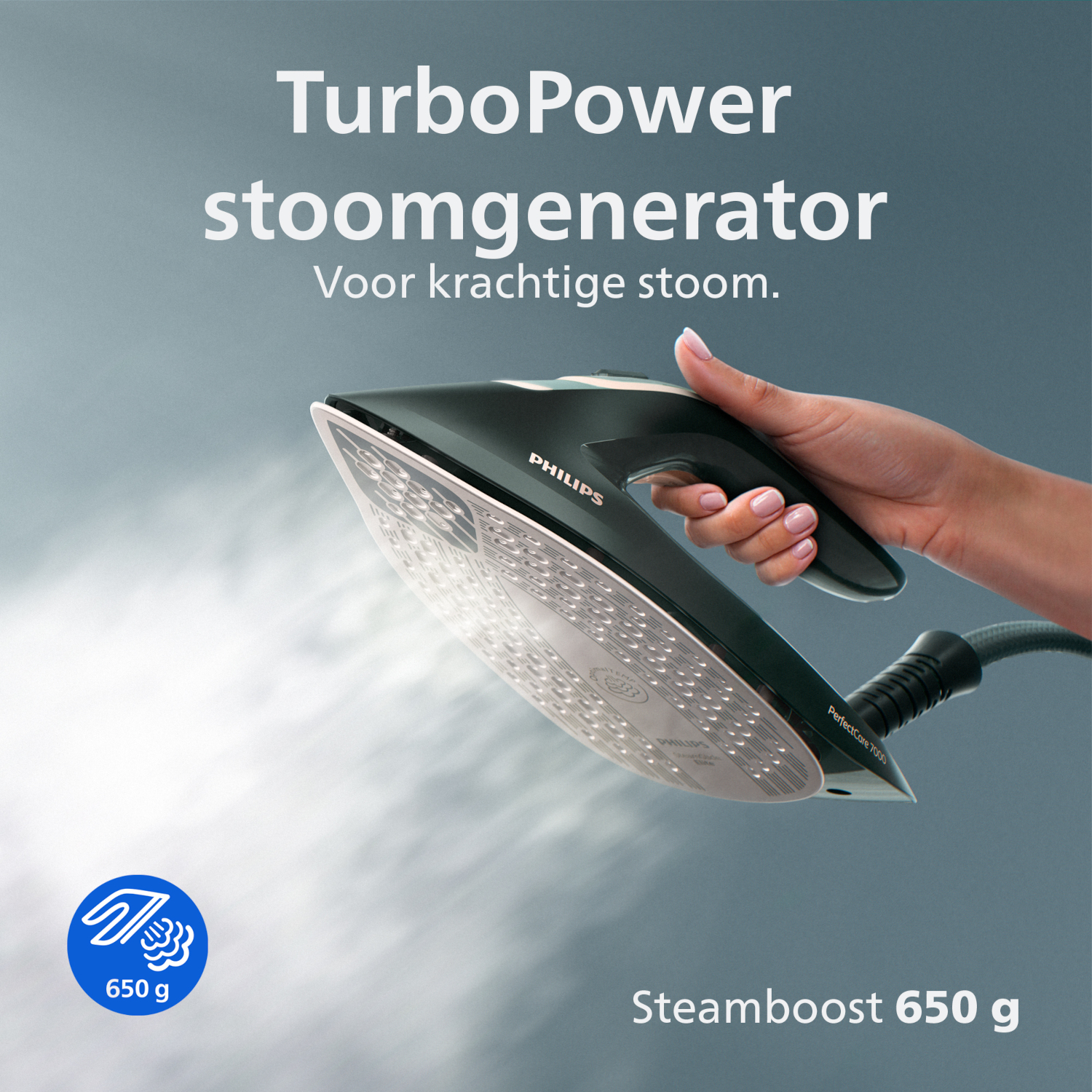 Hand holding a dark green Philips steam generator iron, releasing steam.