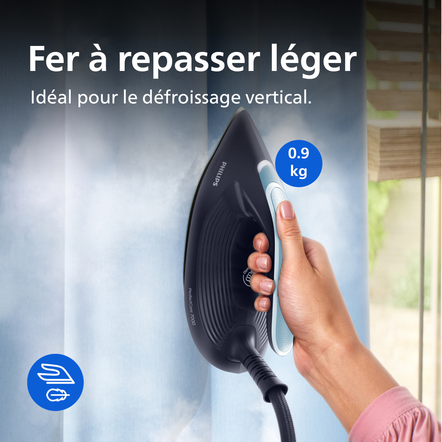 Une main tient un fer noir, projetant de la vapeur sur un rideau. Il pèse 0,9 kg.