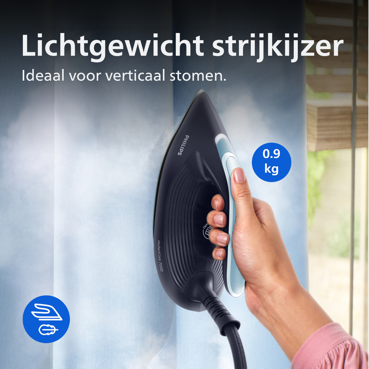 A hand holds a black steam iron, steaming vertically on a blue curtain. 0.9 kg.