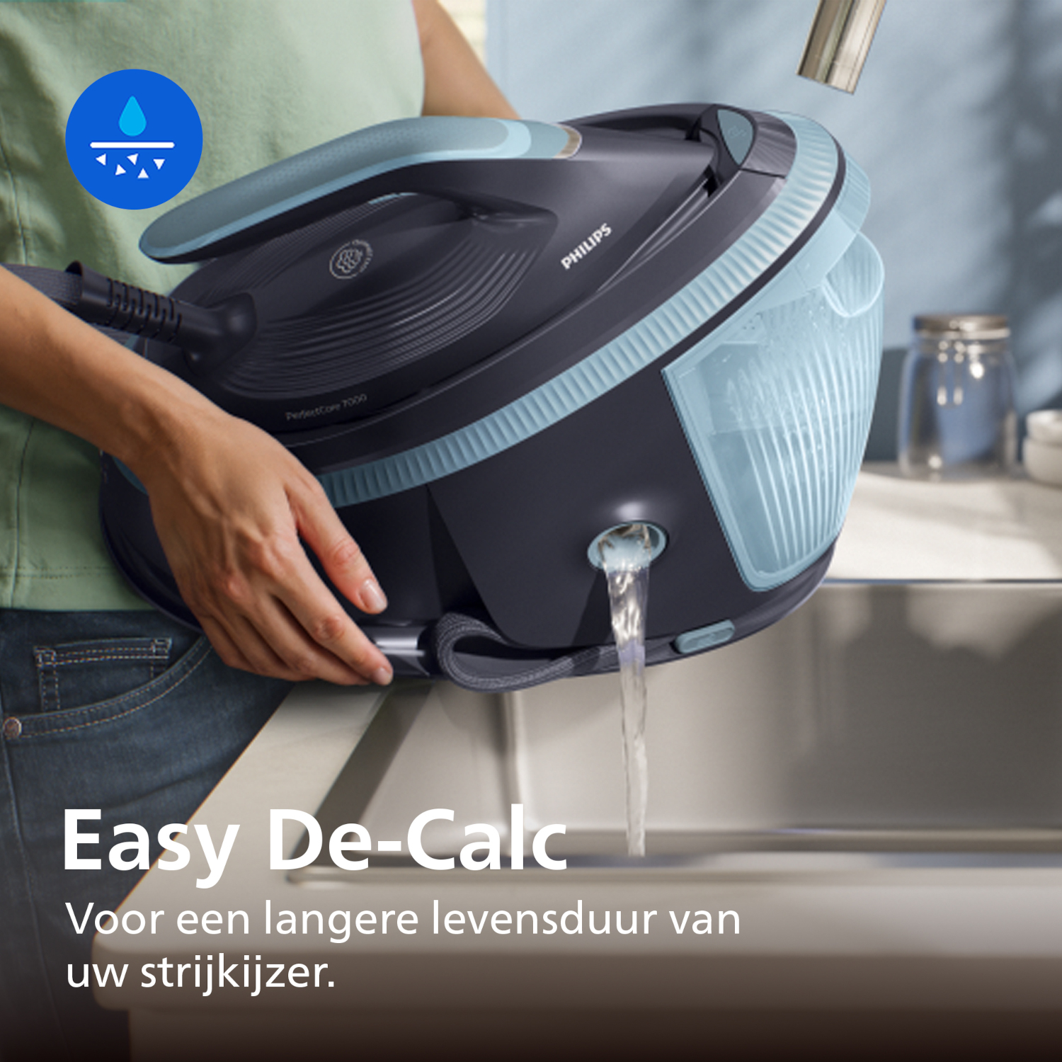 A person empties water from an iron into a sink.