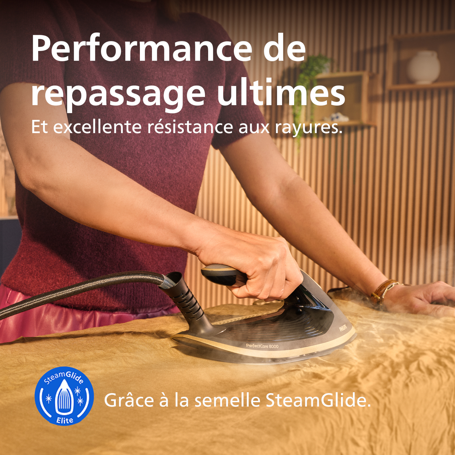 Une femme repasse un tissu jaune avec un fer à vapeur Philips.