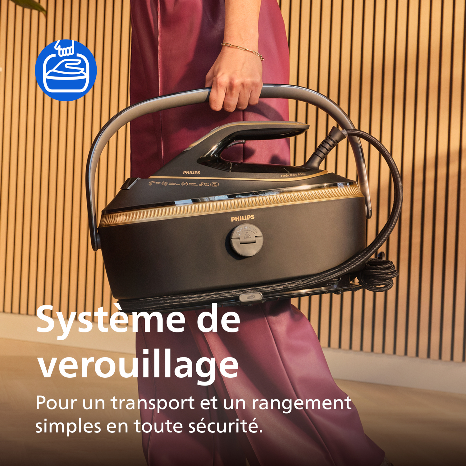 Personne tient fer à repasser Philips avec système de verrouillage. Fond bois.
