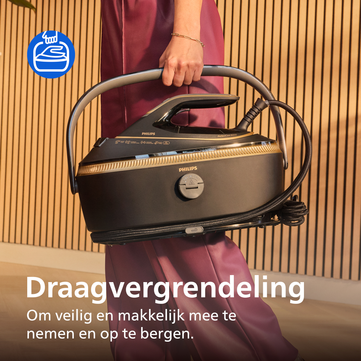 A person holds a black Philips steam iron station with gold accents.