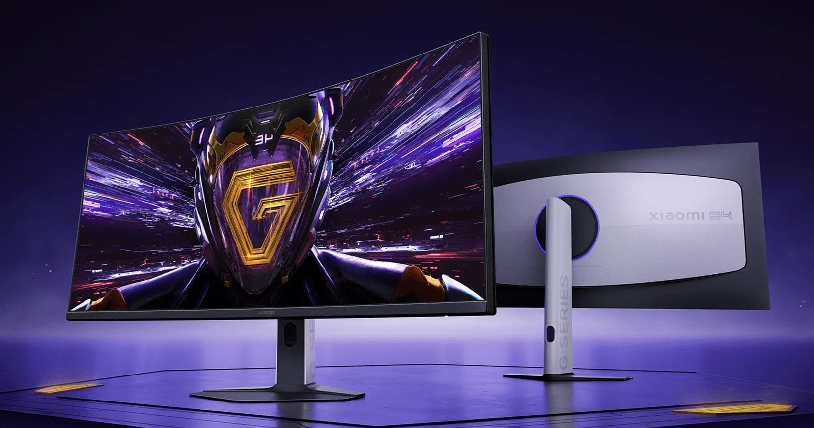 Két ívelt Xiaomi monitor áll egymás mellett lila háttér előtt.