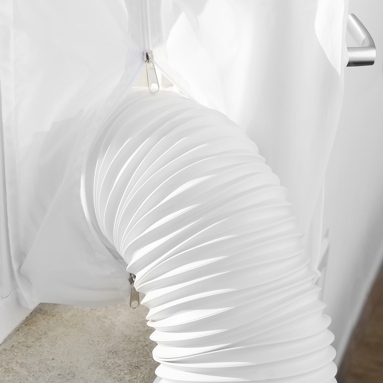 A white flexible hose with pleats emerging from a white zippered fabric section.