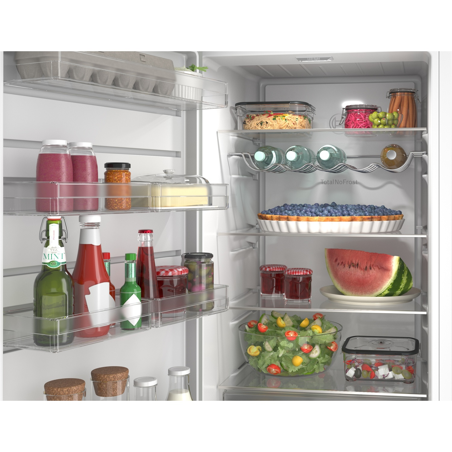À l'intérieur d'un réfrigérateur : œufs, jus, bocaux, salade, pastèque, tarte, pâtes et boissons.
