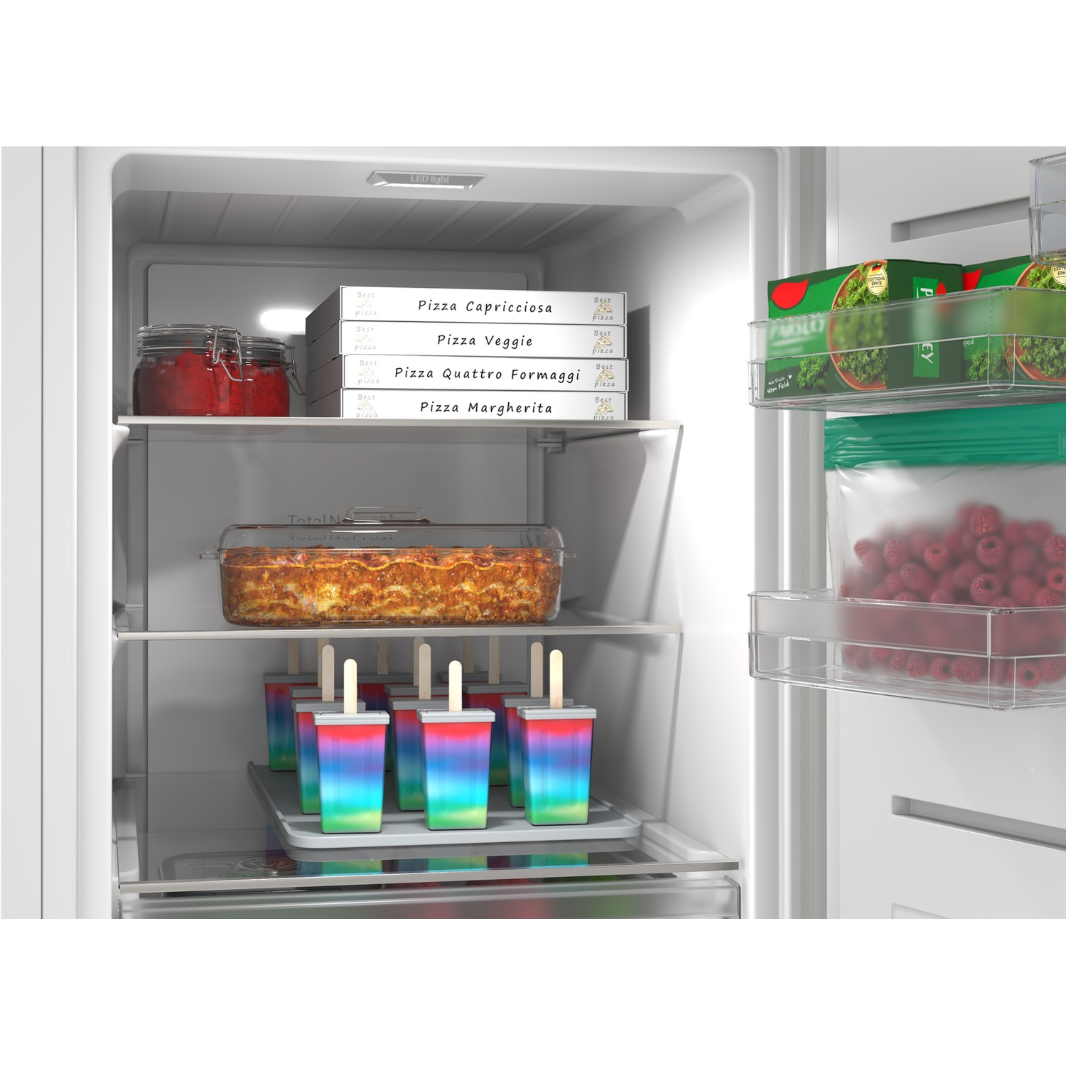 Dans un réfrigérateur : pizzas, lasagnes, glaces à l'eau, framboises et salade.