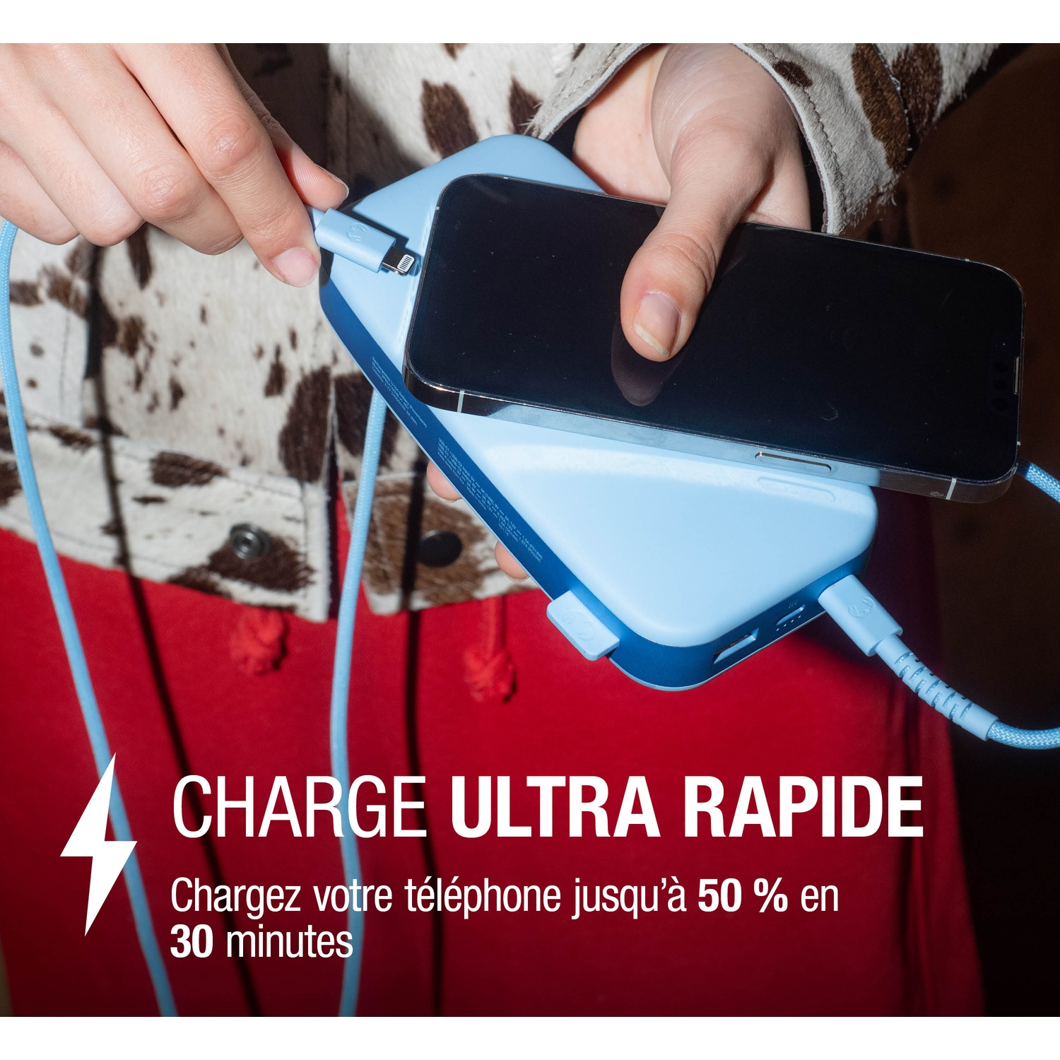 Une main connecte un câble de chargement à un ensemble téléphone-power bank bleu clair.