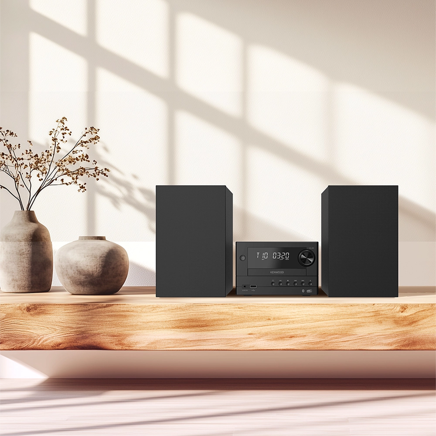 Kompaktes schwarzes Stereo-System mit zwei Lautsprechern und Vase auf Holzregal.
