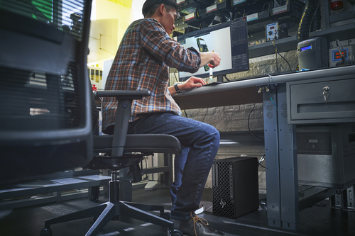 Hombre con camisa a cuadros se sienta en un escritorio, trabajando en una computadora.
