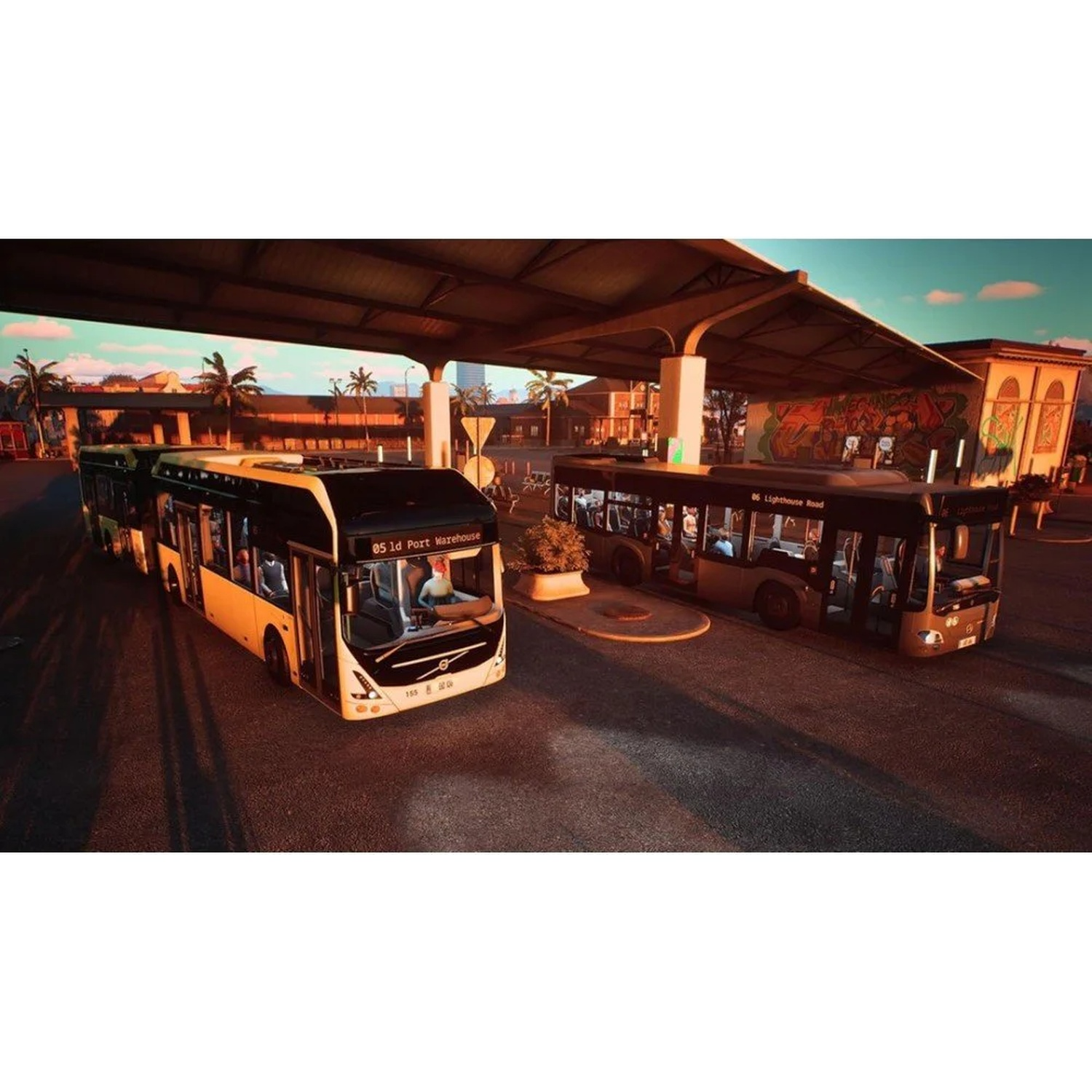 Deux bus sous un auvent, avec des palmiers et des bâtiments en arrière-plan.