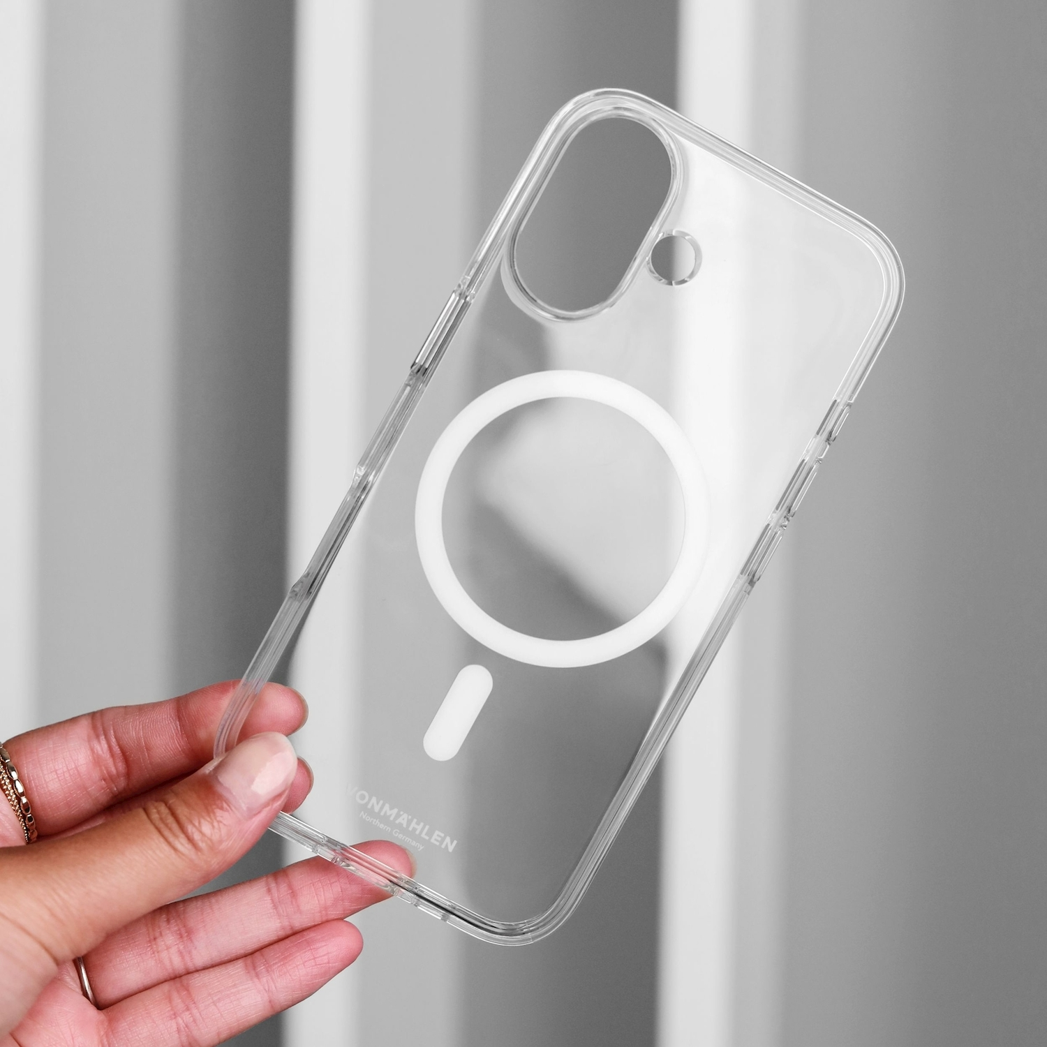 Una custodia trasparente per telefono con anello MagSafe bianco è tenuta da una mano.