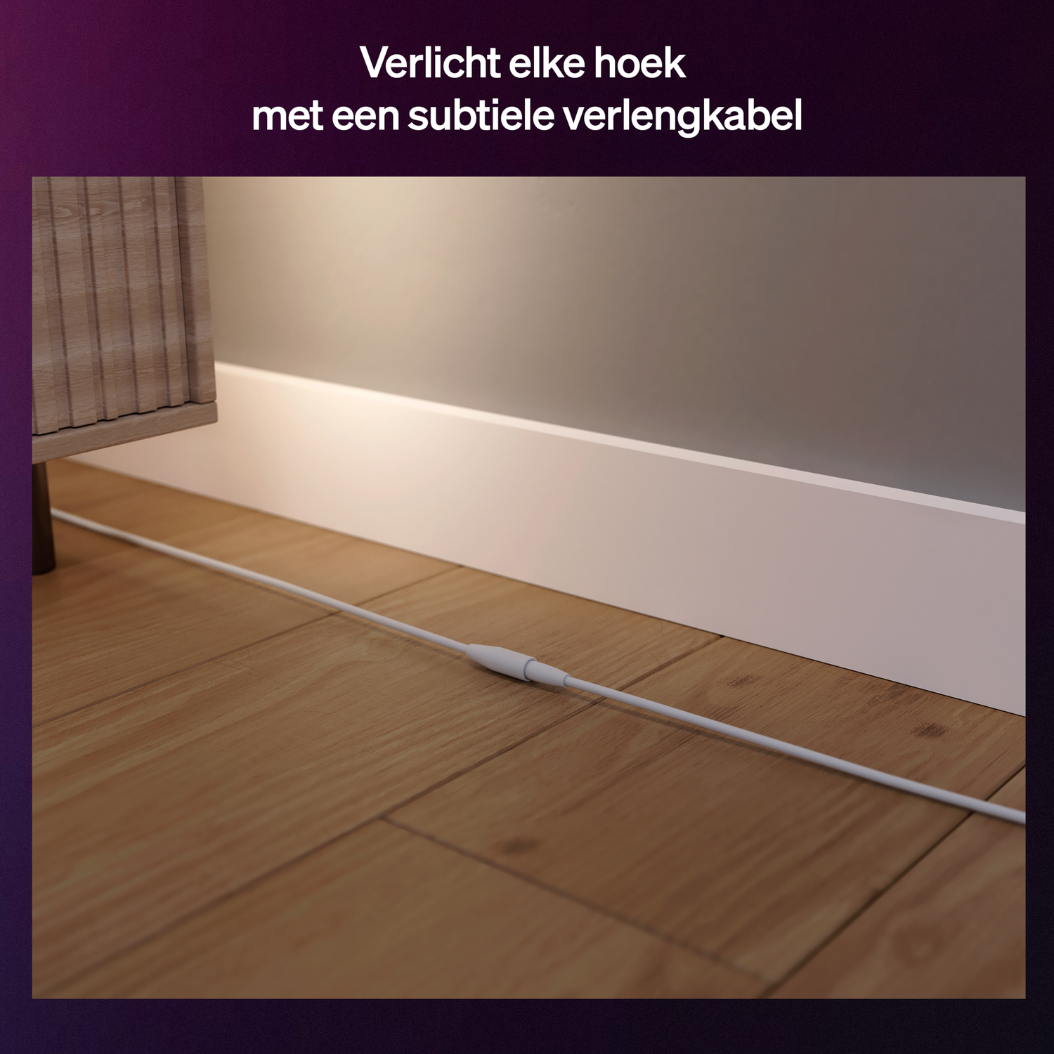 Een wit verlengsnoer ligt op een houten vloer naast een witte plint.