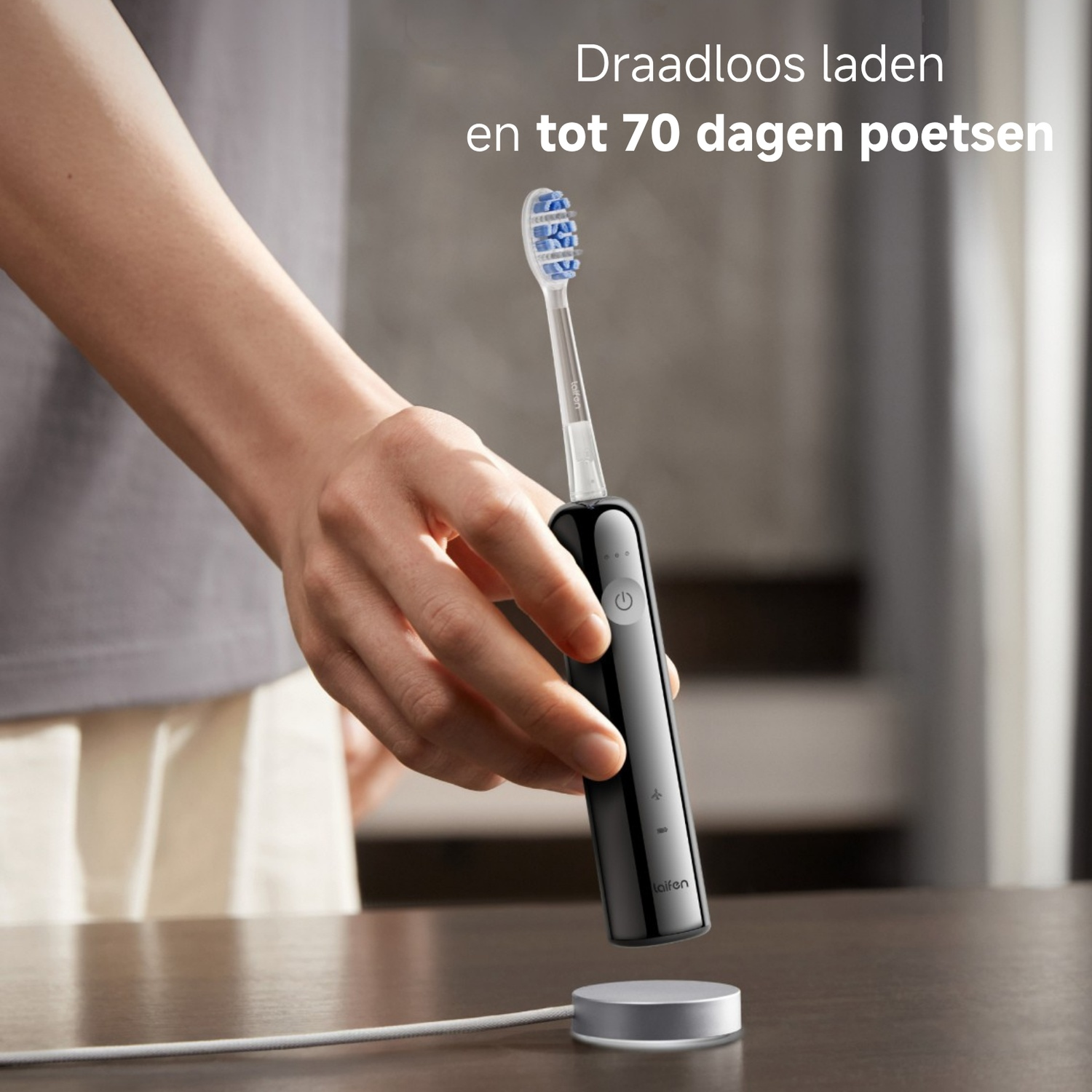 Hand houdt zwarte elektrische tandenborstel boven laadstation. Draadloos laden.