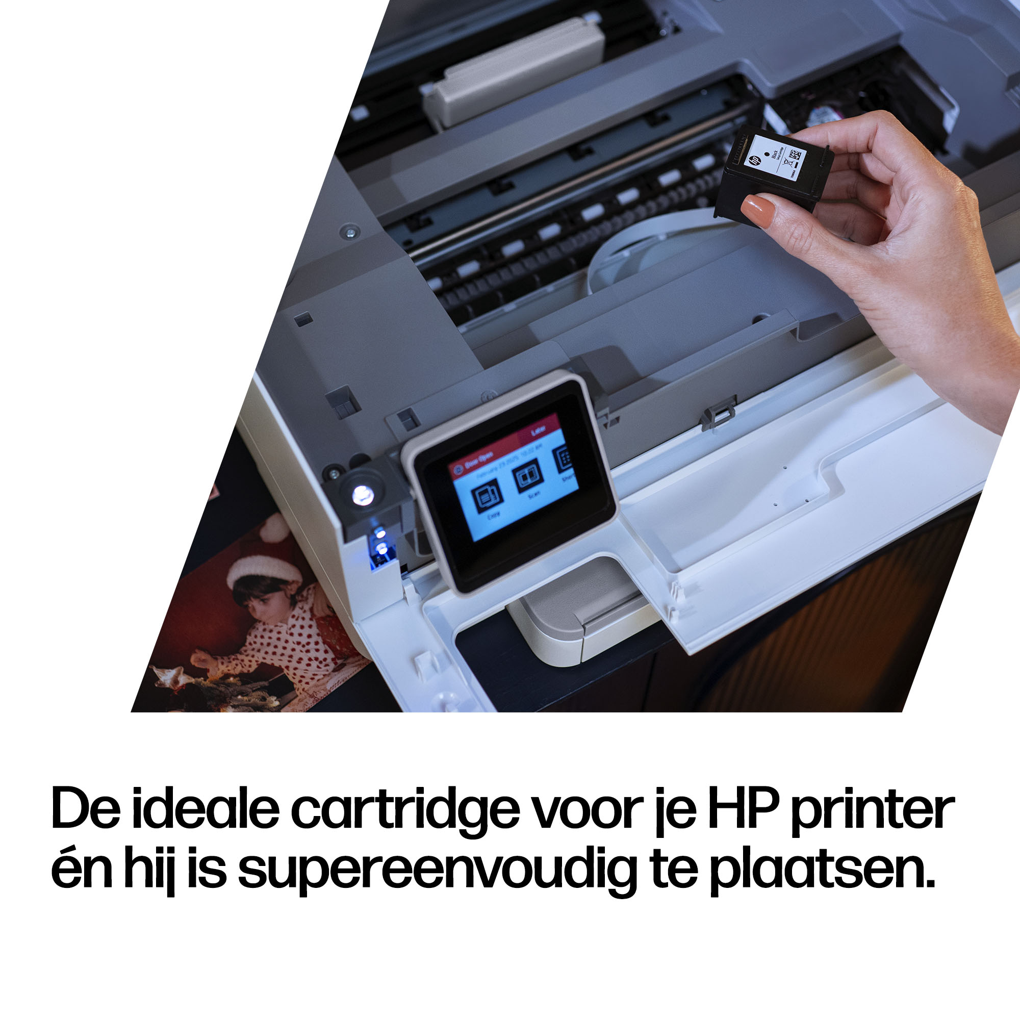 A hand holds a black ink cartridge over a printer with a small screen.