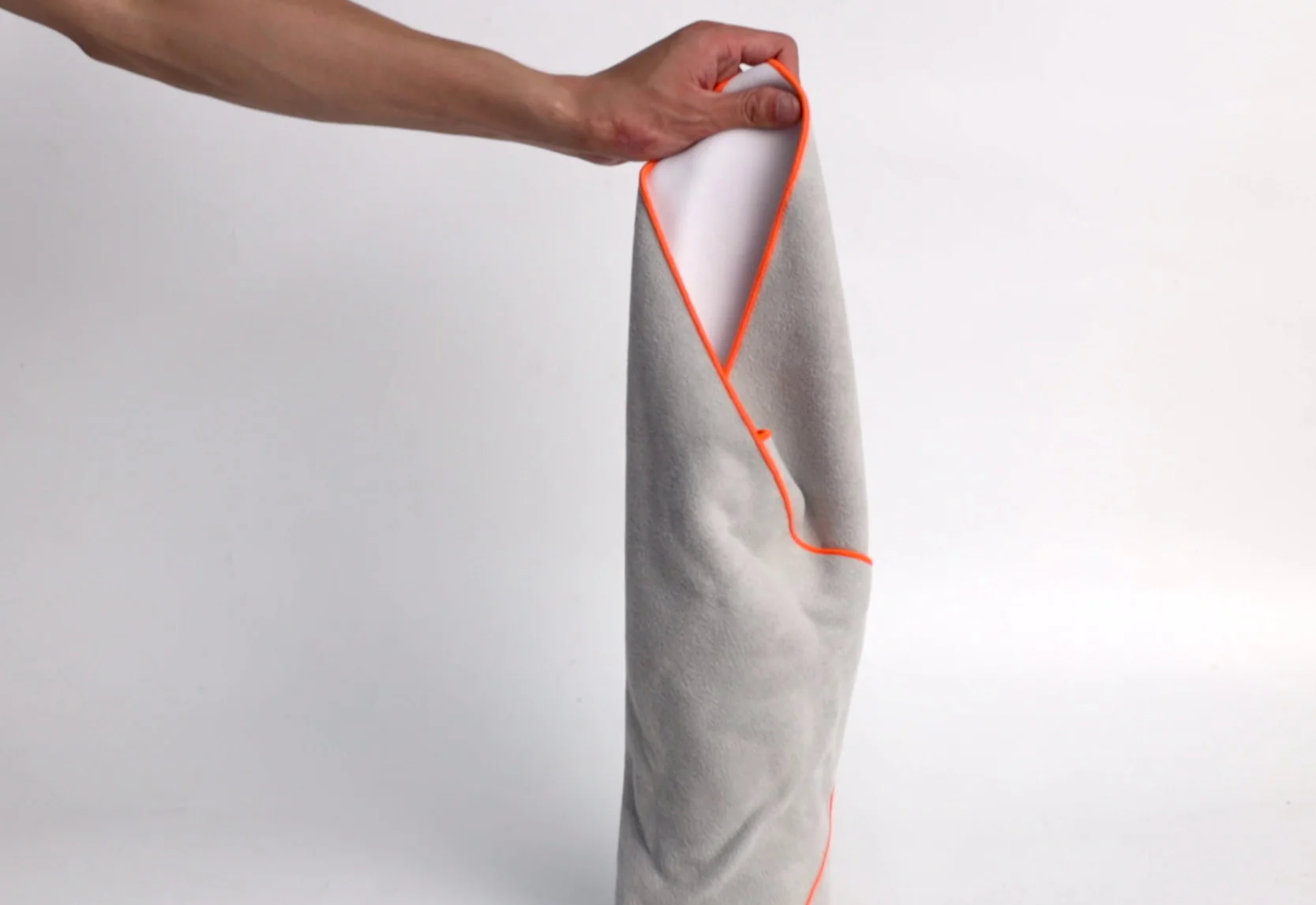Ein Arm hält ein graues Handtuch mit orangefarbener Umrandung.
