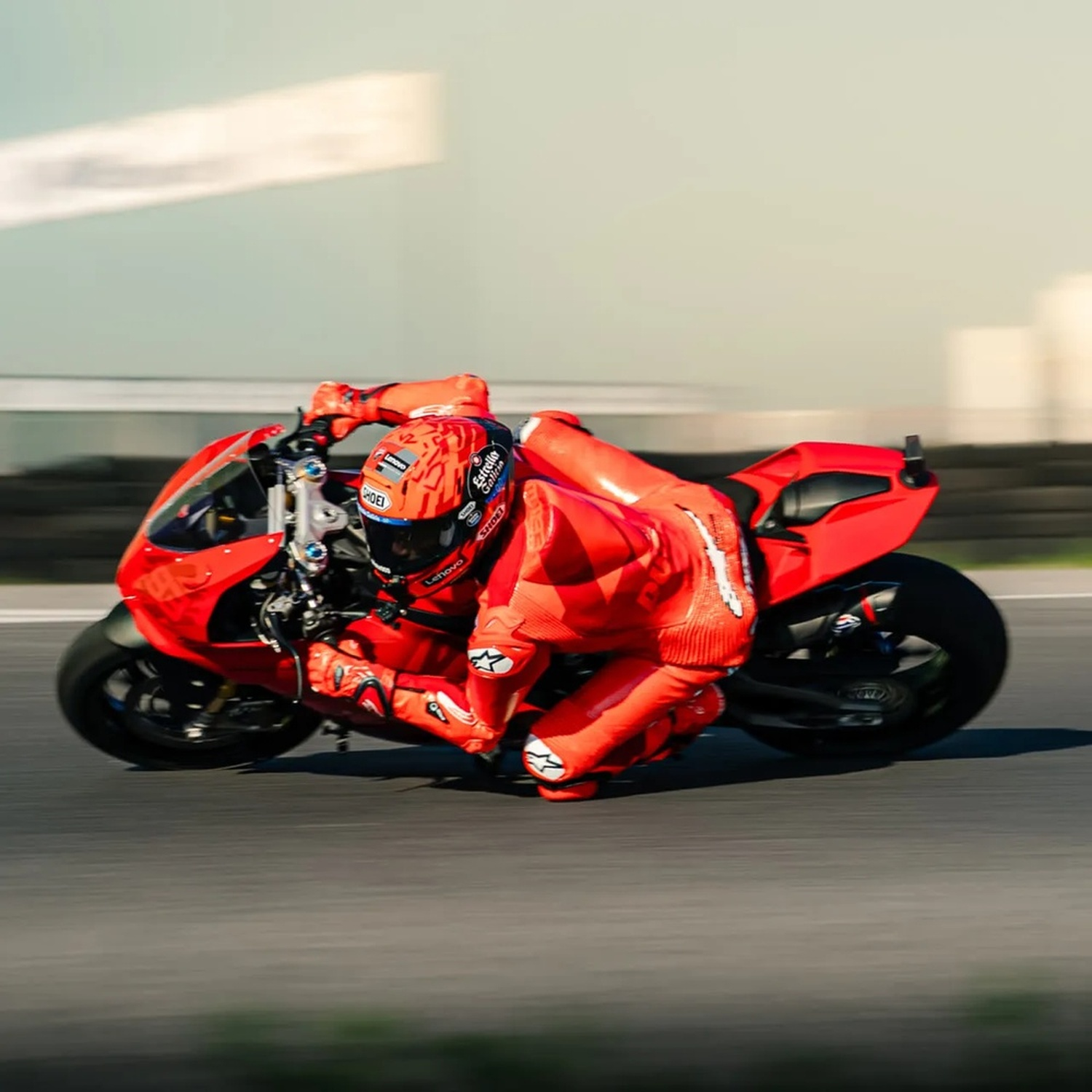 Un pilota in tuta rossa si piega in curva su una moto rossa su una pista.