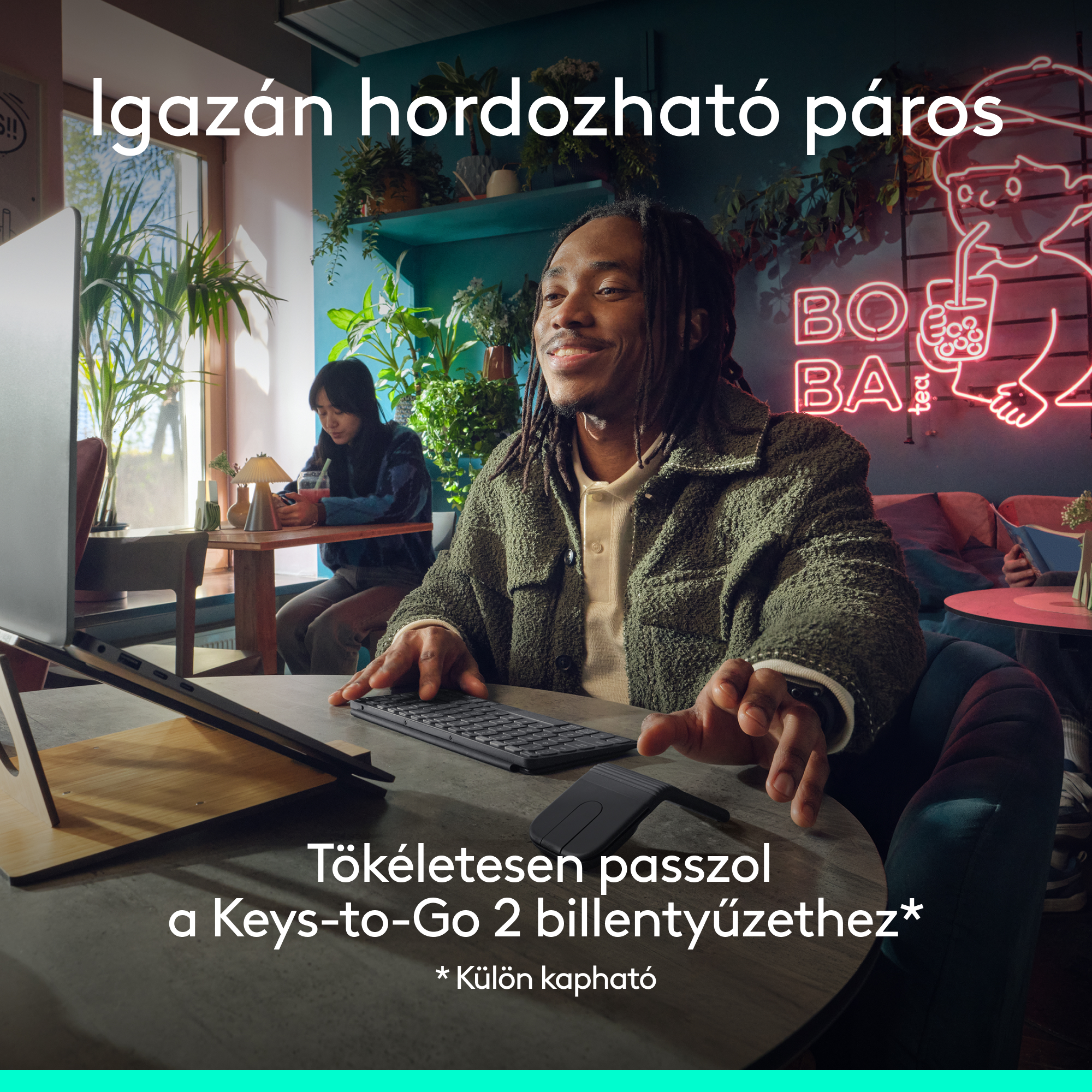 Férfi gépel kávézóban neonfelirattal.
