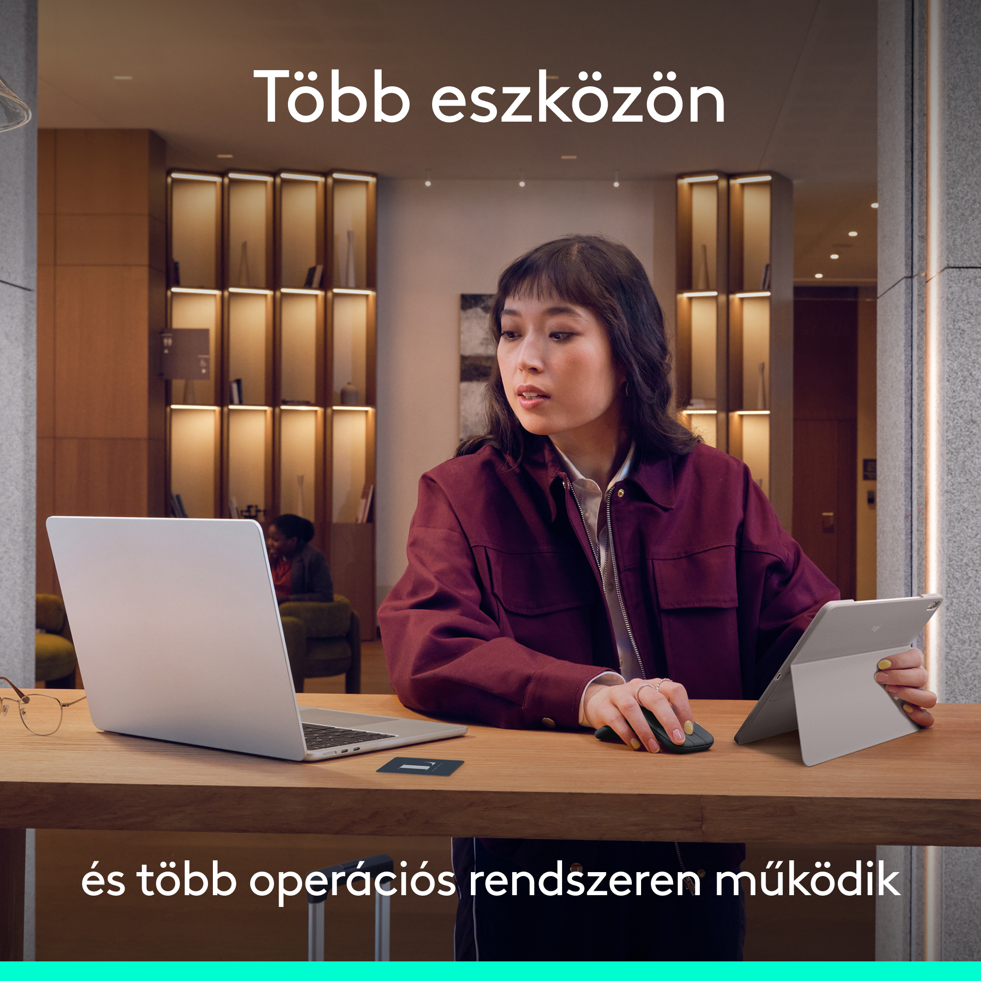 Nő laptopon dolgozik egérrel és tablettel. Belső tér polcokkal.
