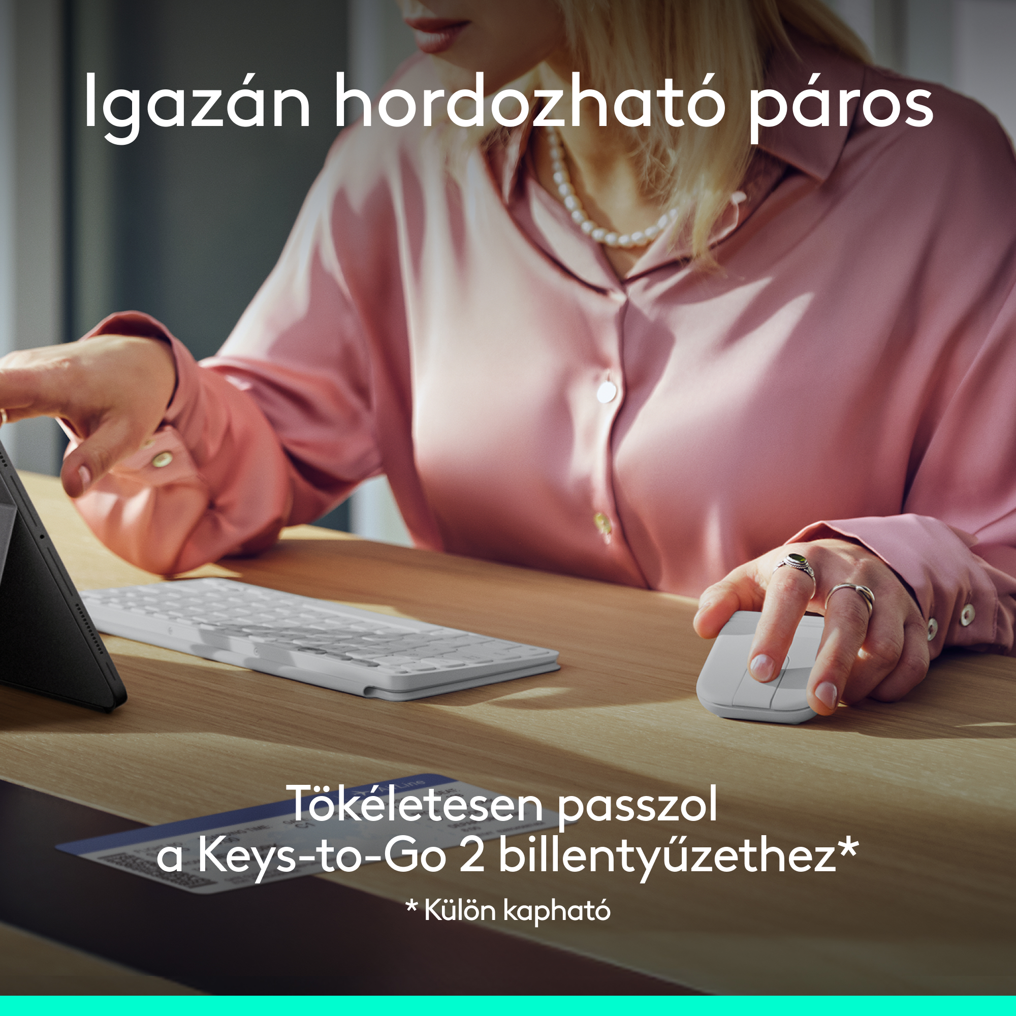 Egy nő fehér egeret és billentyűzetet használ egy faasztalon.
