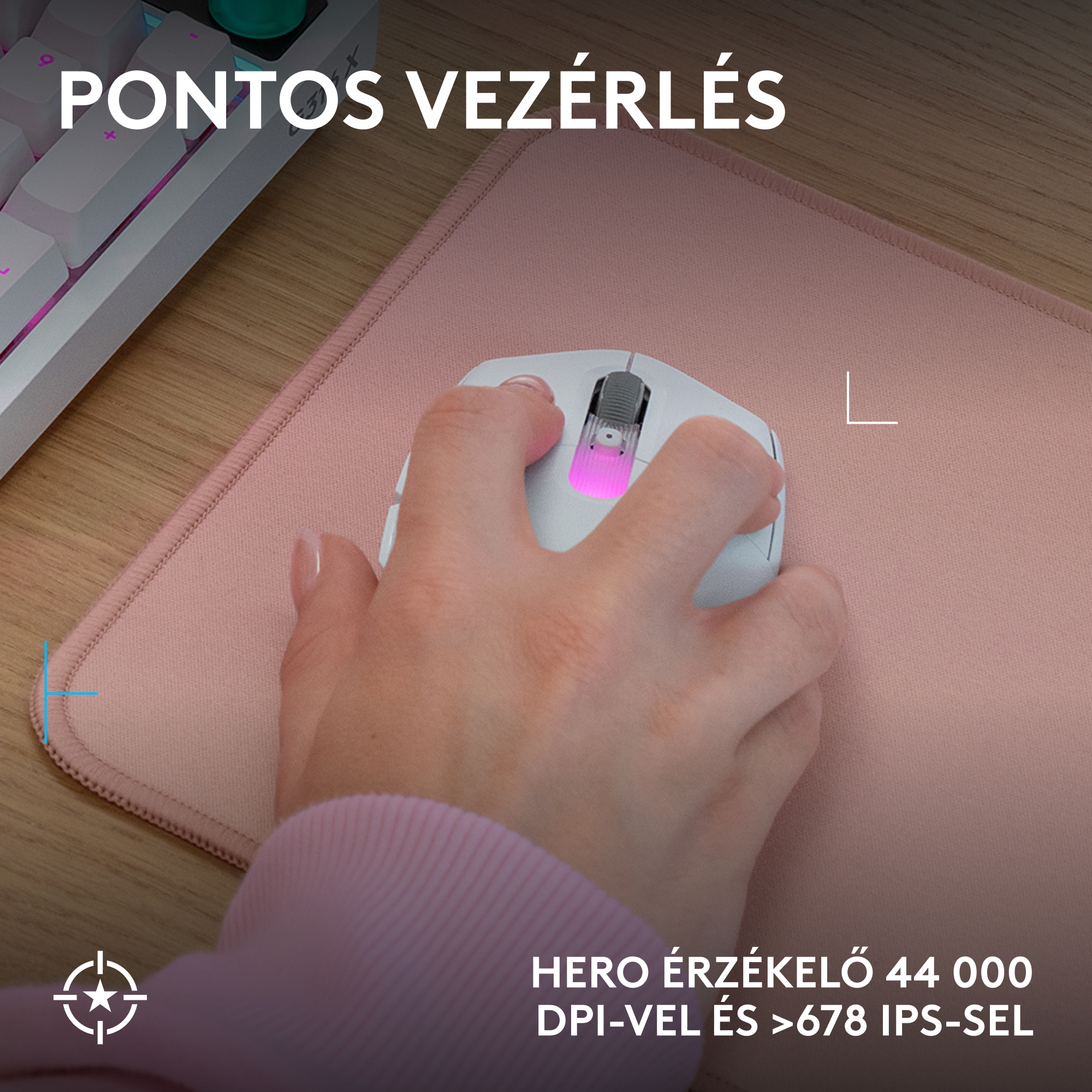 Kéz egérrel rózsaszín egérpadon, billentyűzet a háttérben.