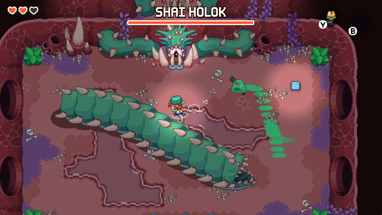 Personaje pixelado lucha contra jefe gusano verde en cueva con hongos morados.