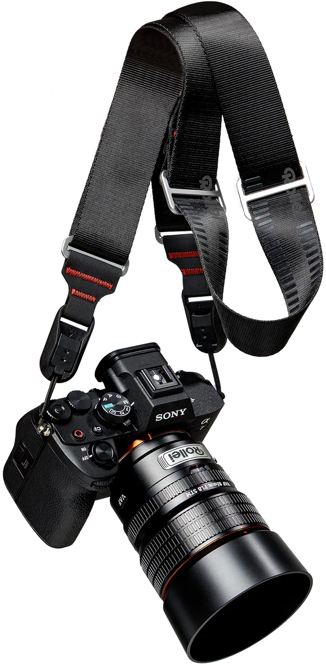 Eine schwarze Sony-Kamera mit Rollei-Objektiv und schwarzem Gurt vor schwarzem Hintergrund.