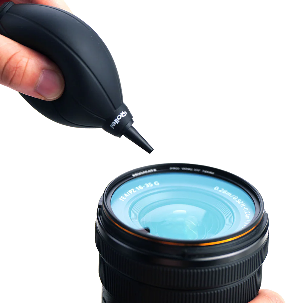 Una mano stringe una pompetta aria nera verso un obiettivo della fotocamera con riflesso blu.
