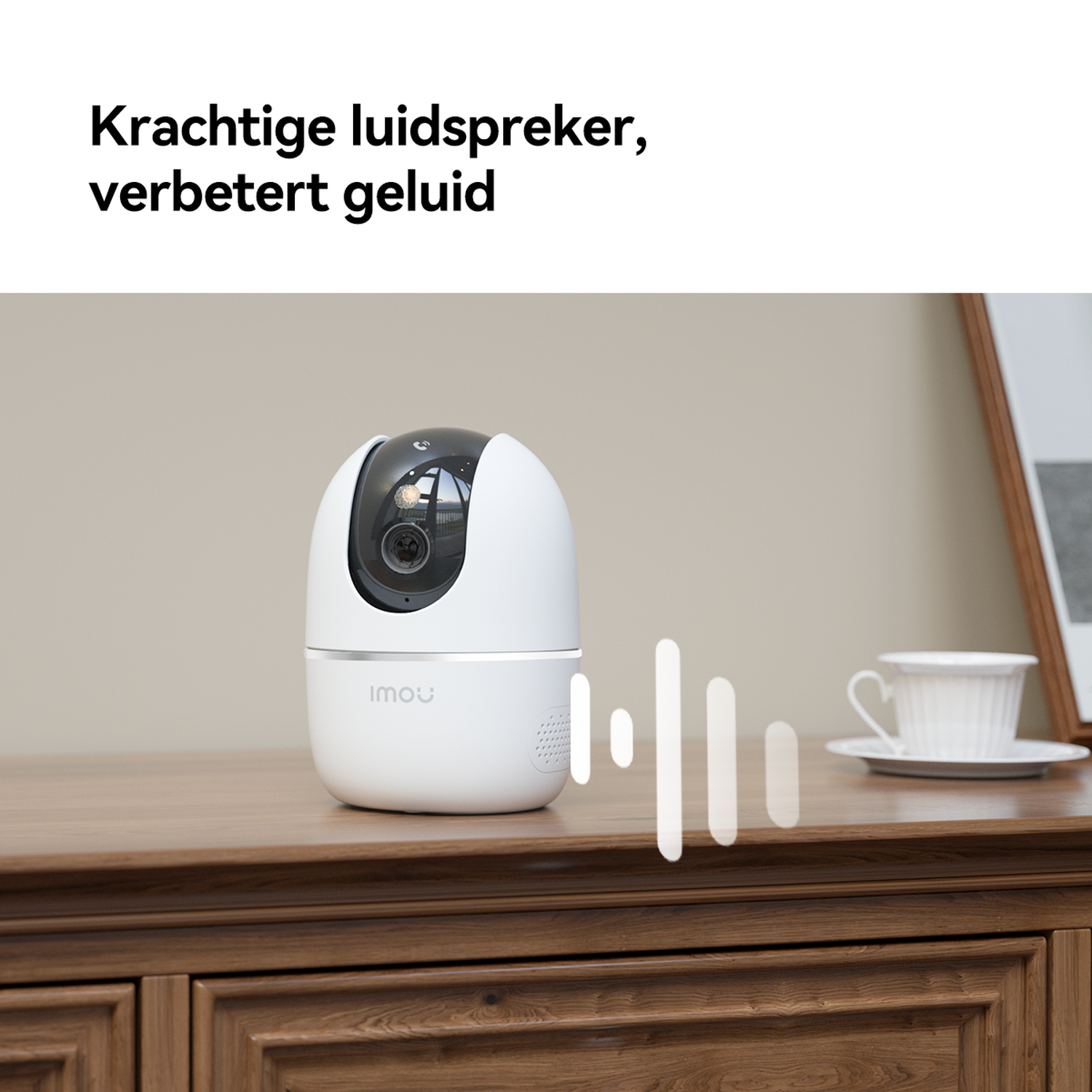 A white speaker with camera sits on a wooden cabinet, next to a cup.