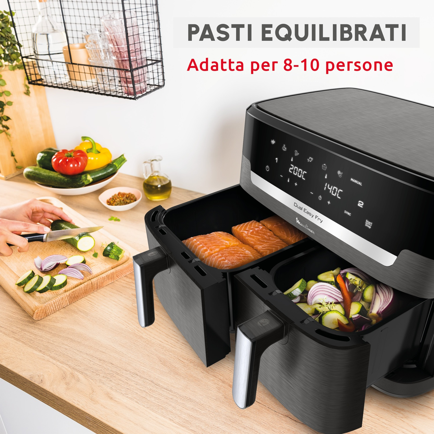 Una friggitrice ad aria doppia con salmone e verdure, accanto a un tagliere con zucchine e cipolle.
