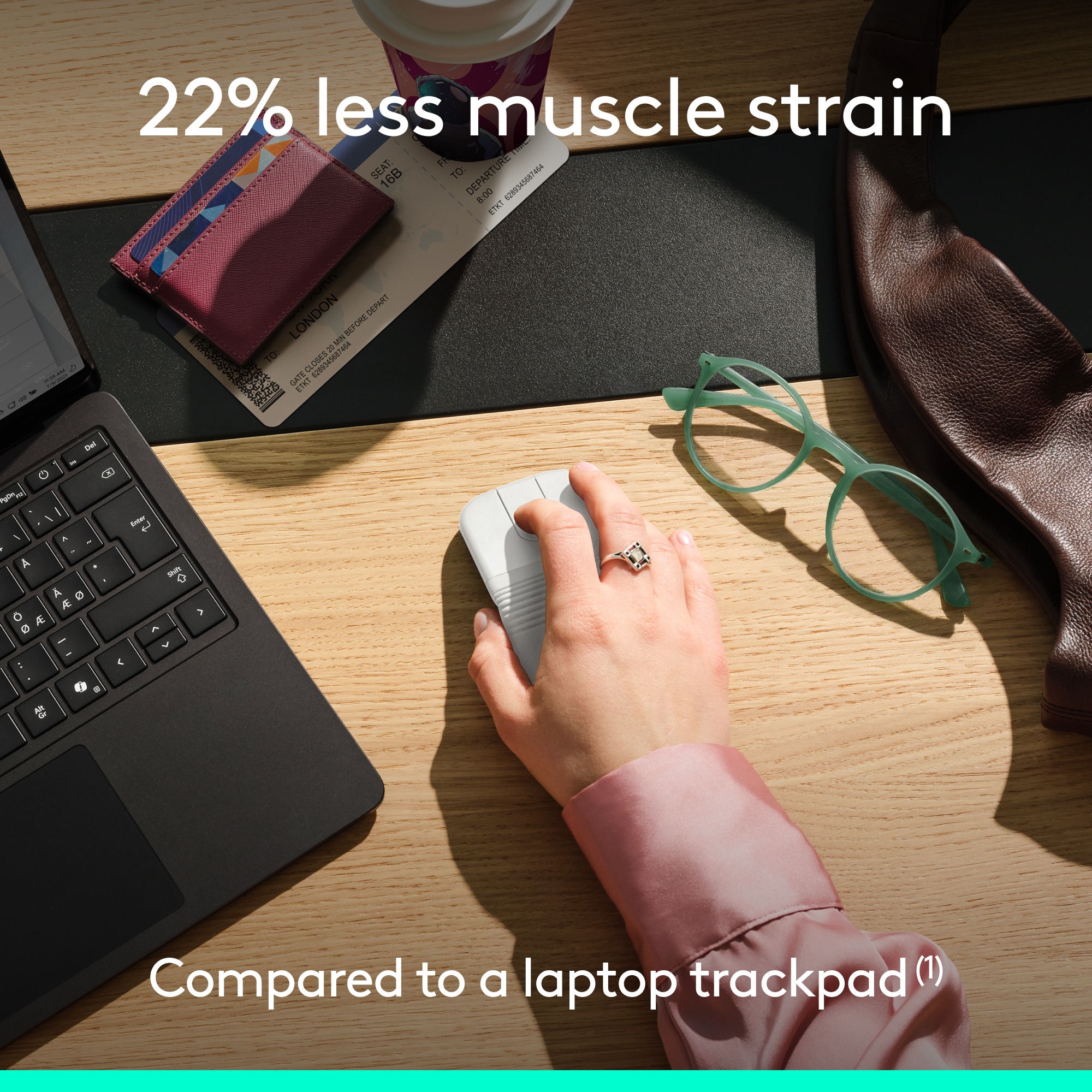 Una mano usa un mouse bianco accanto a un laptop, portafoglio e occhiali su una scrivania.