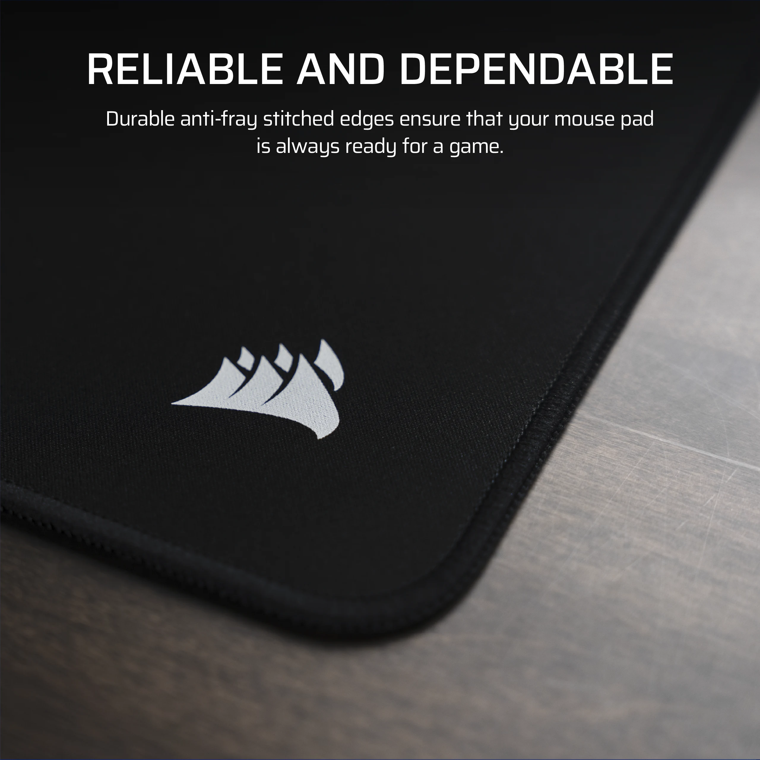 Tapis de souris noir avec logo blanc et bords cousus sur fond bois.