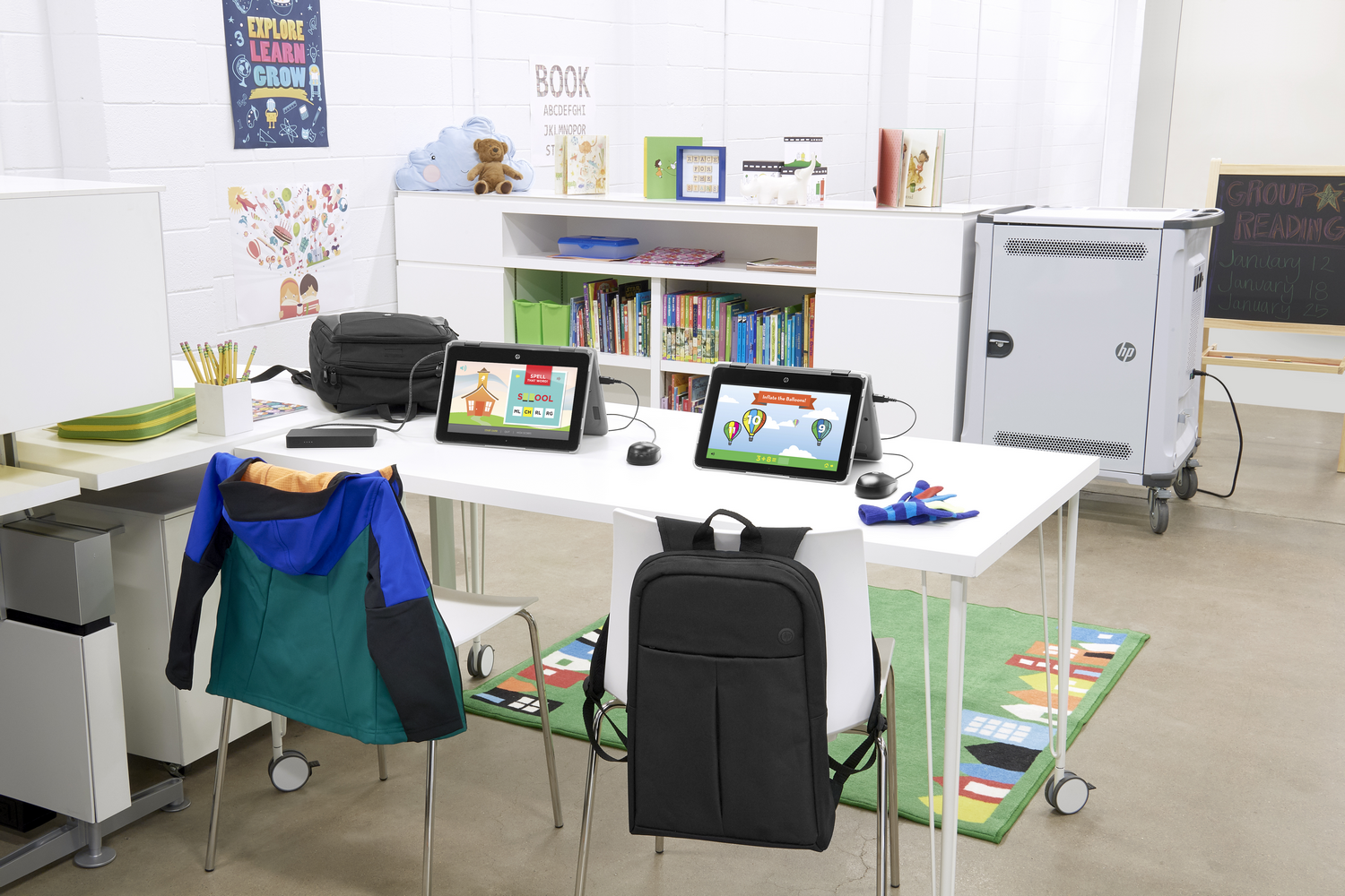 Un aula con dos tabletas, mochilas y un carrito.